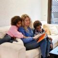 Parent reading a picture book with two children, illustrating raising bilingual children