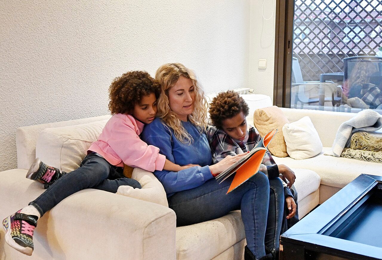 Parent reading a picture book with two children, illustrating raising bilingual children